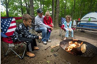 Family Camping at park roasting hot dog over fire.